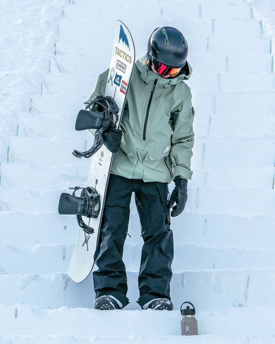 snowboarder stands on snowy steps 