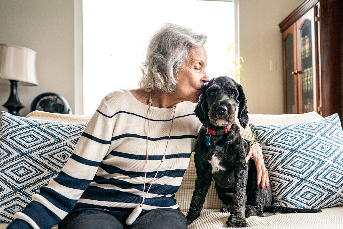 Older lady kissing her dog’s ear 