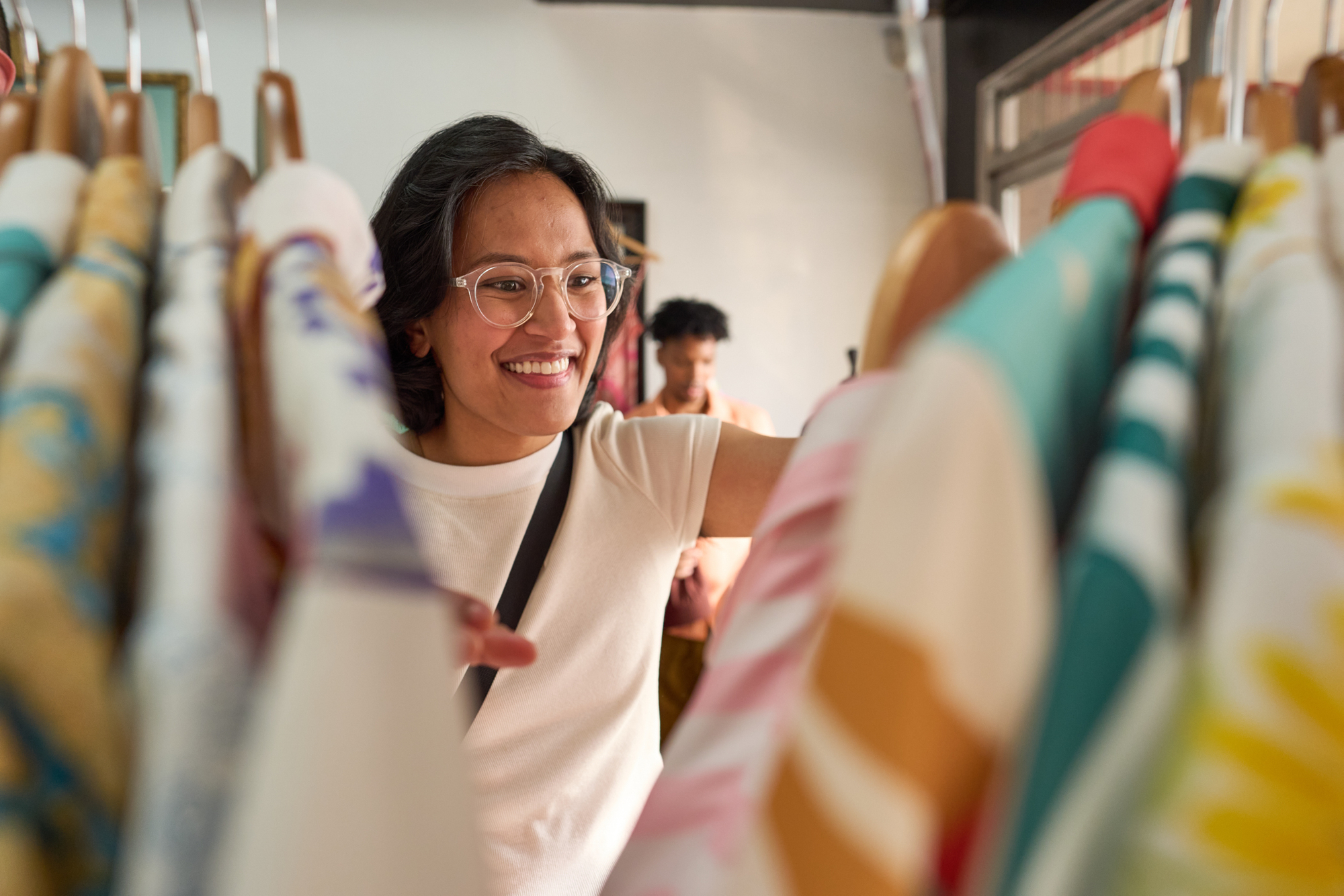 woman pushes through clothing searching for the perfect top to buy with her premier rewards visa Premier Visa