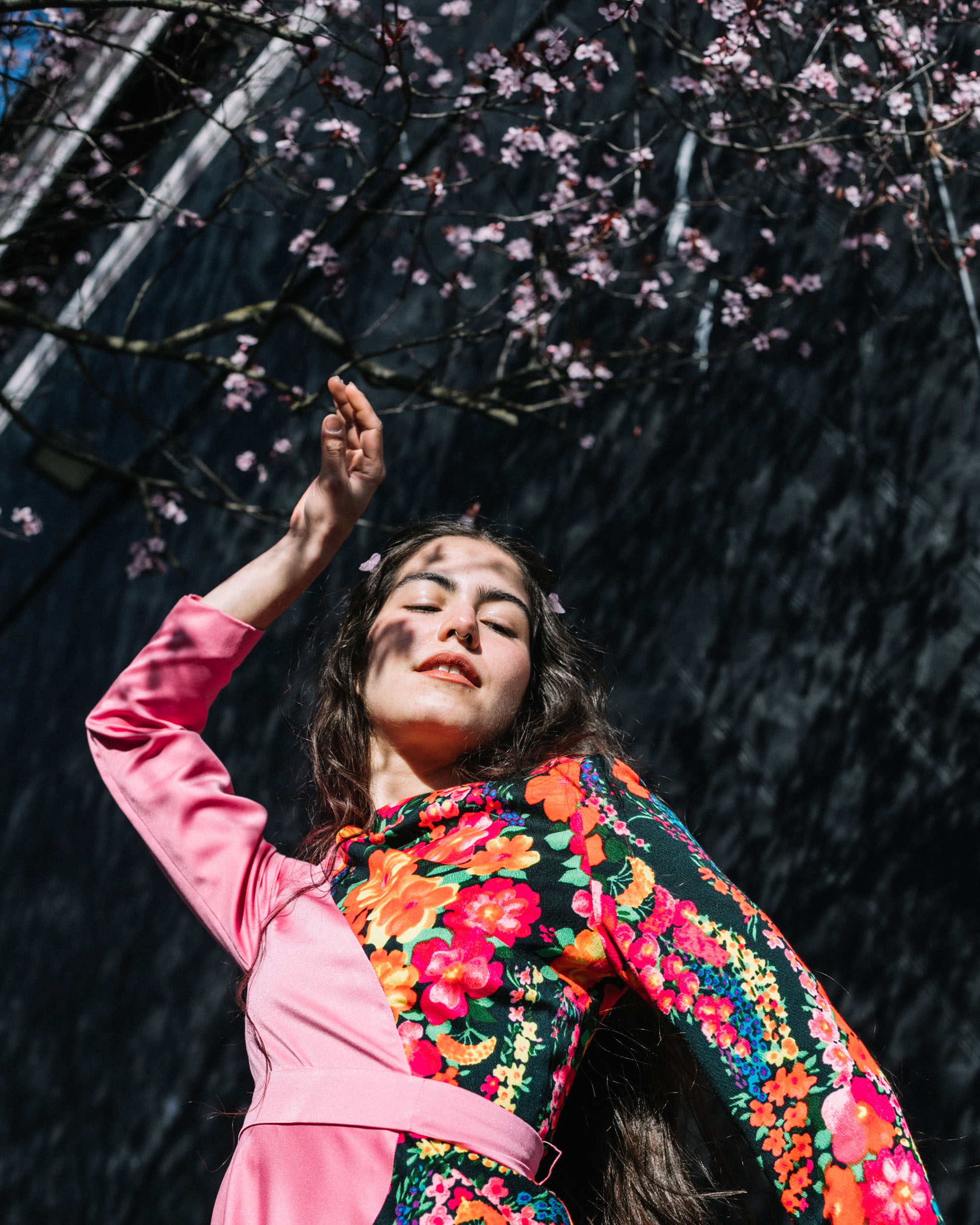 woman in vibrant floral patterned pink top dances under the cherry blossoms styled by Mark Humphreys - Los Angeles Fashion Stylist for Commercial, TV, and Film