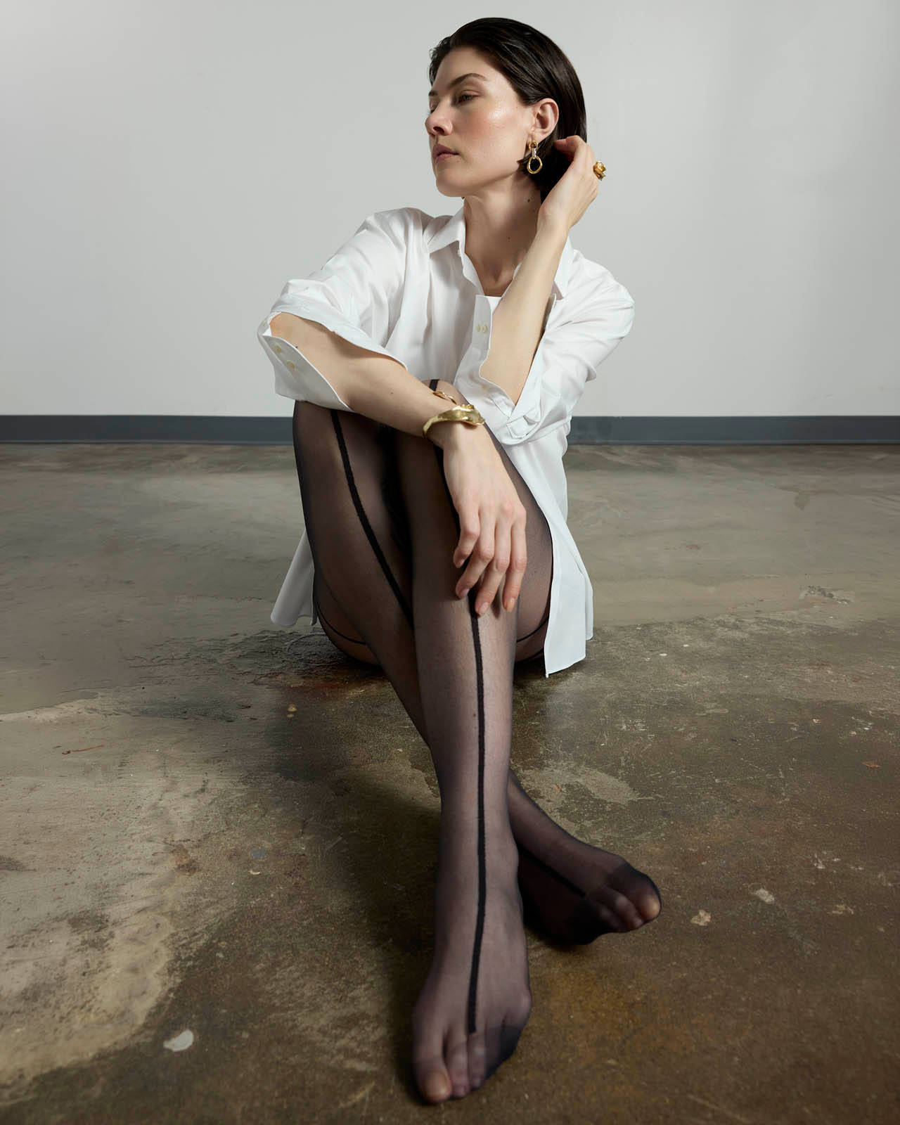 woman in white button down, gold jewelry and black striped tights 