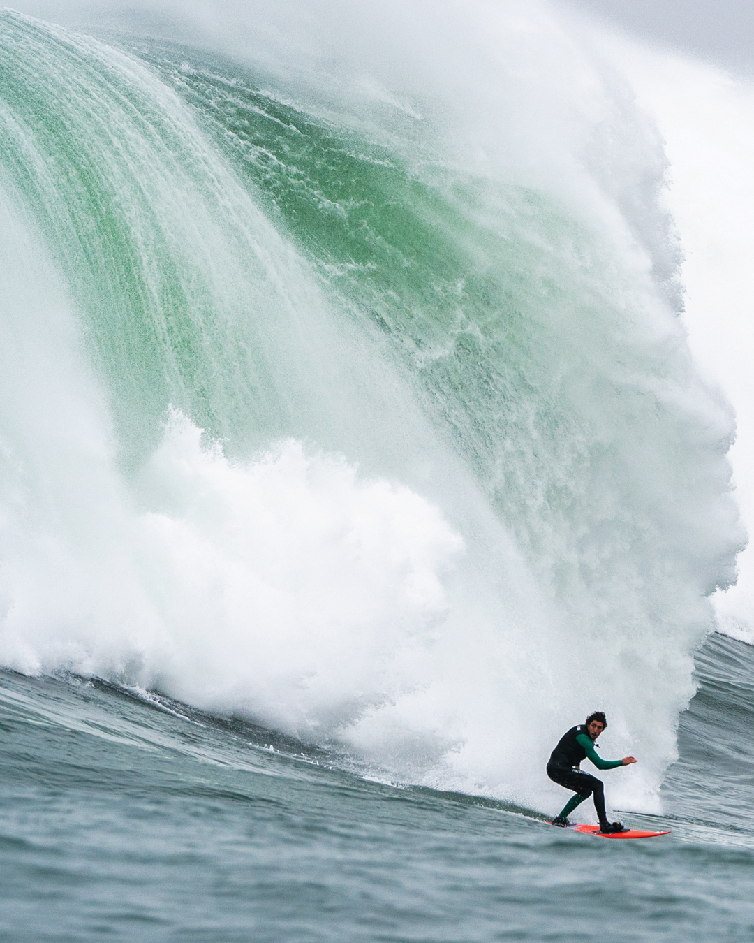 surfer comes off of a giant wave at surfing competition 