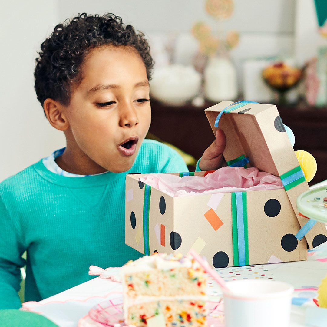little boy opens a birthday present at a birthday party