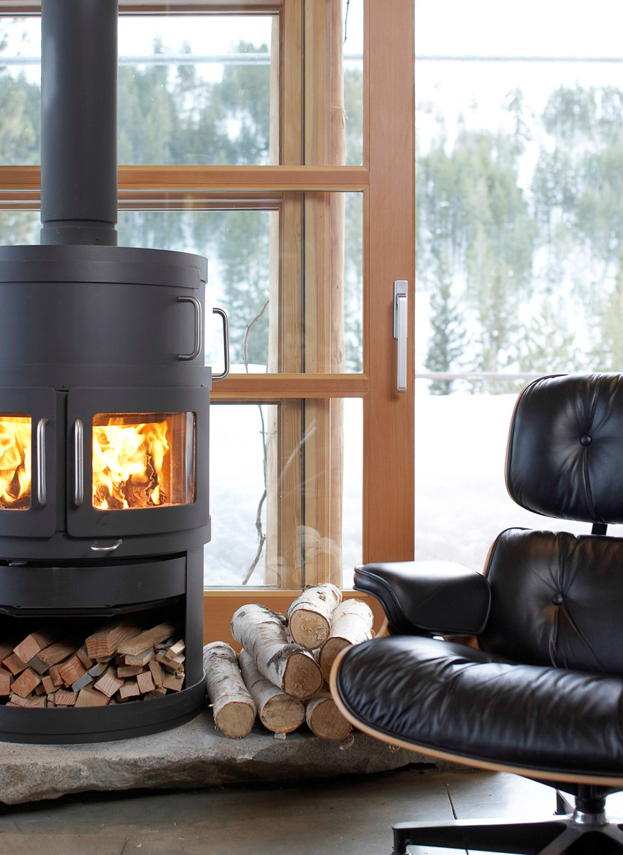 leather chair by a modern fireplace with snow peeking through the windows 