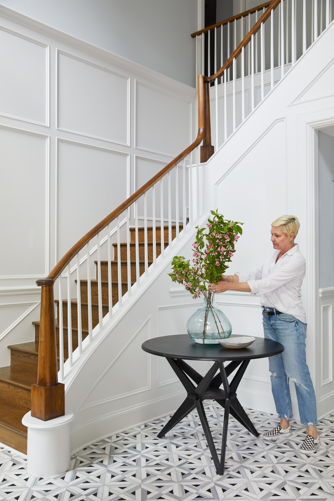 Stunning white entryway and geometrical floor Portrait of a woman arranging flowers in entryway