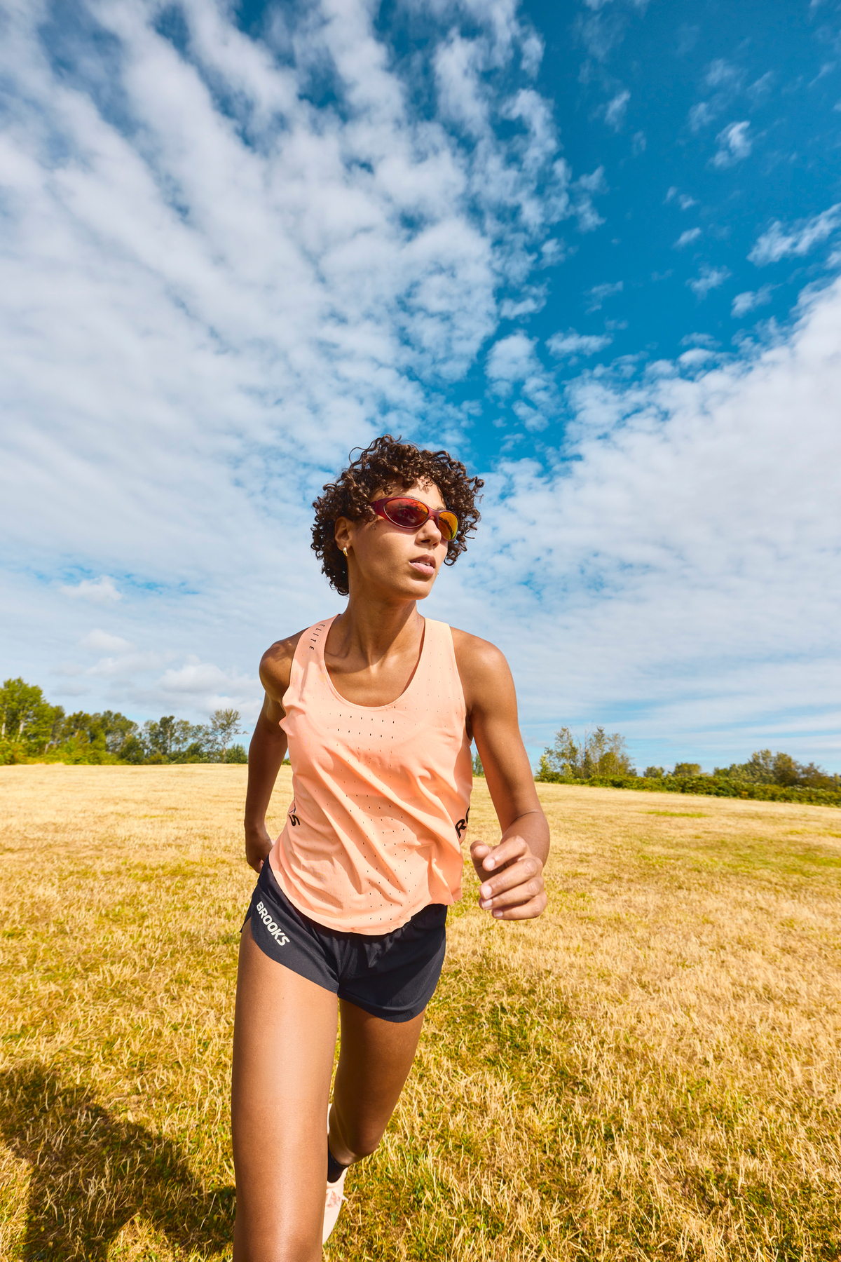 woman runs through field in her brooks running gear 