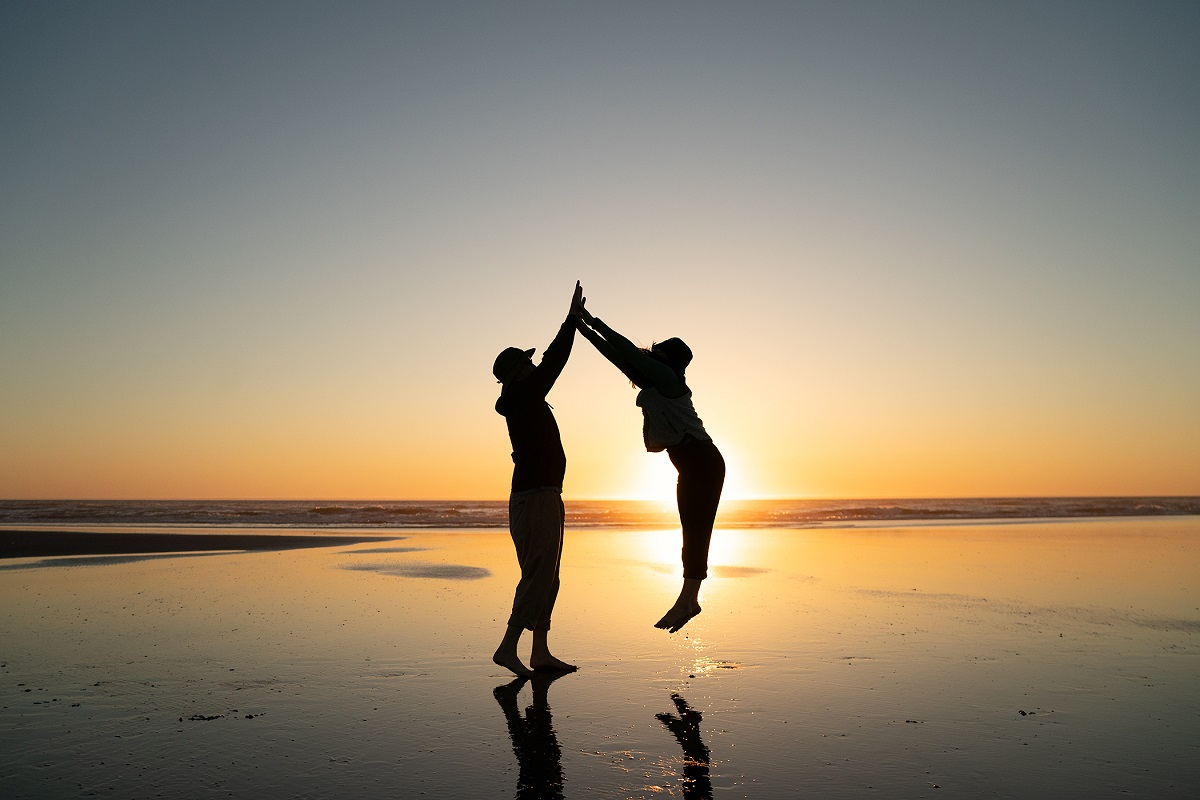 sunset beach walk  youn couple high fives on the beach