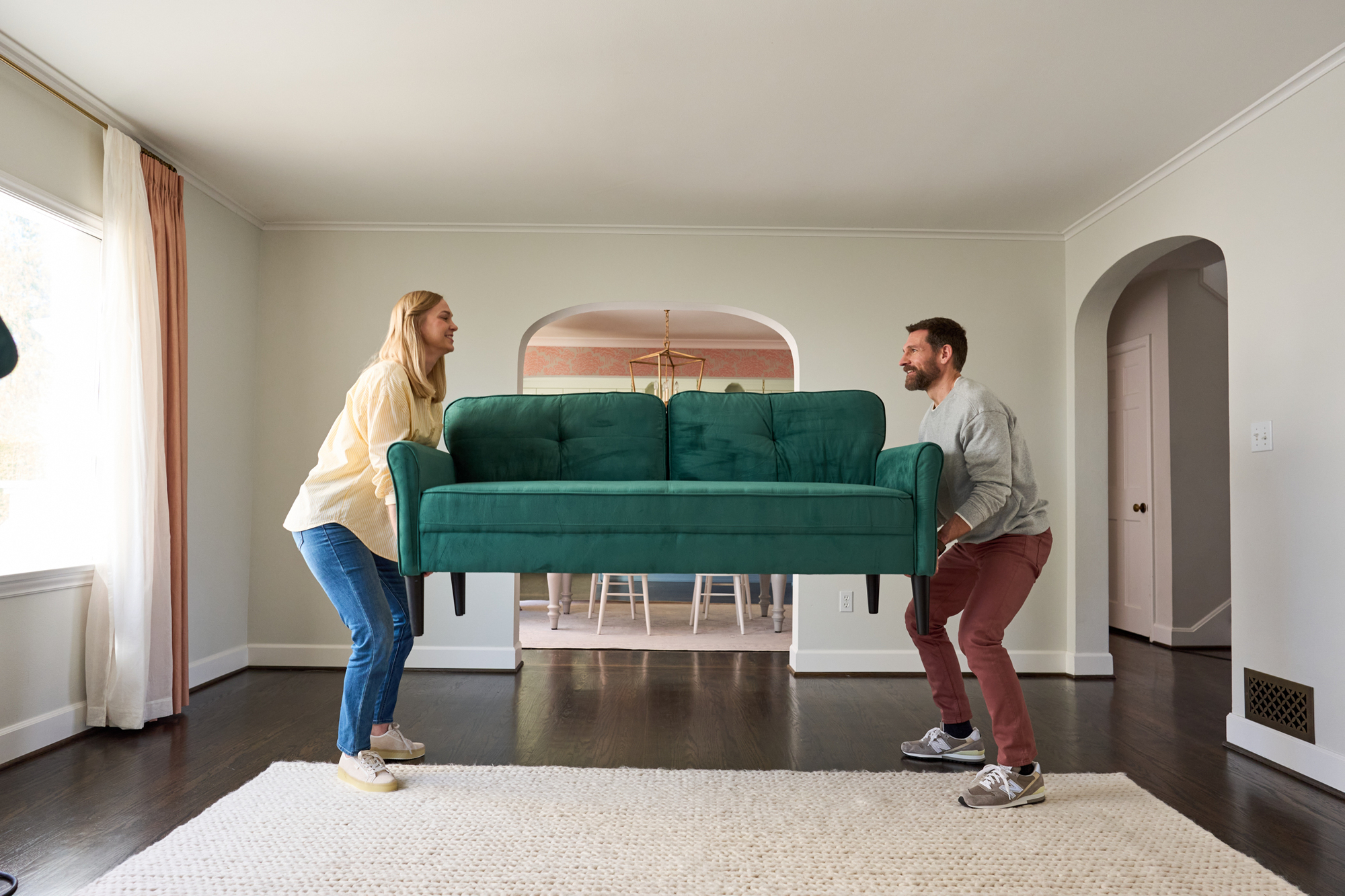 a couple brings their new sofa into the living room Moving In