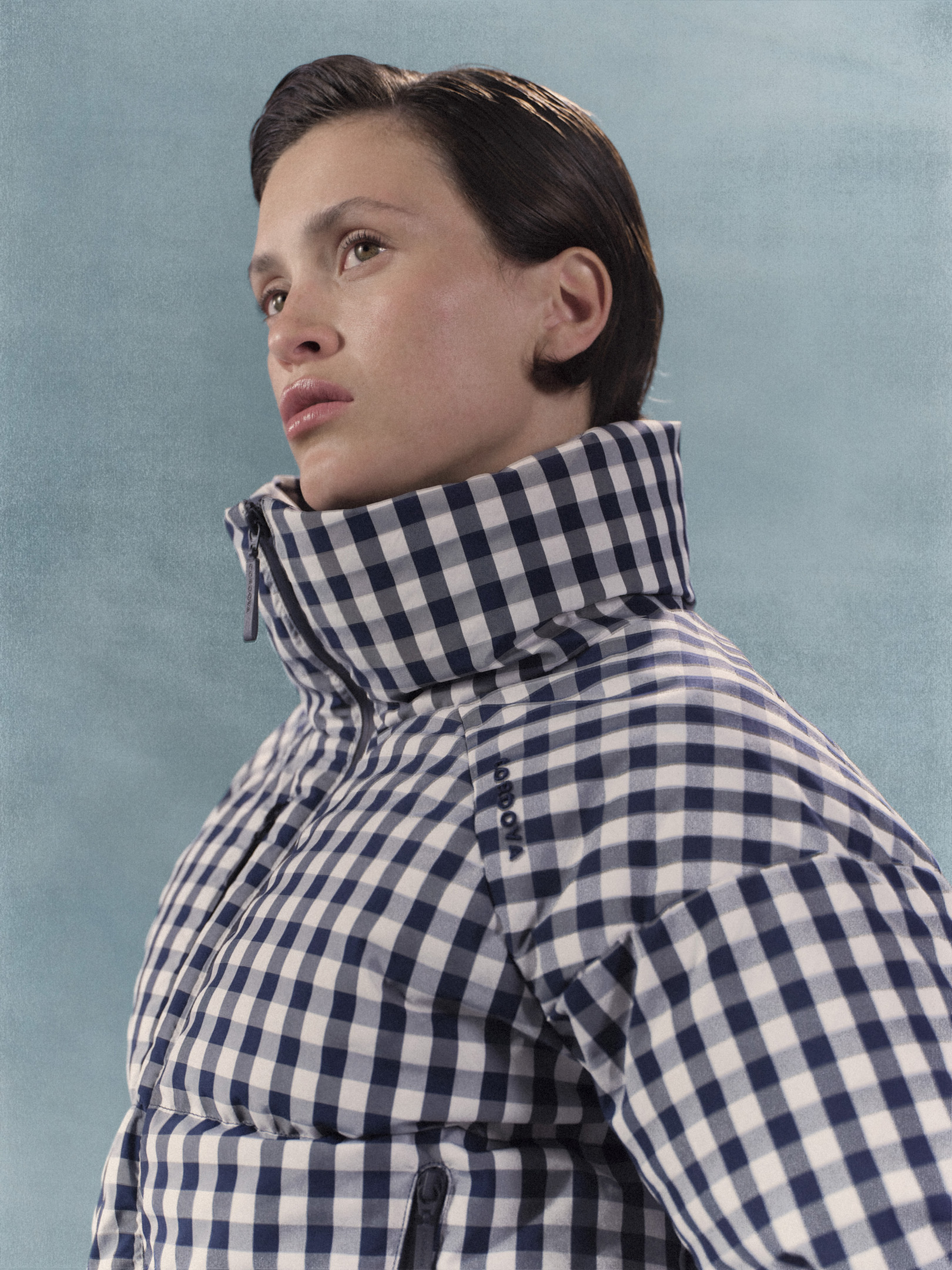 model poses in cordova puffer jacket in front of blue backdrop 