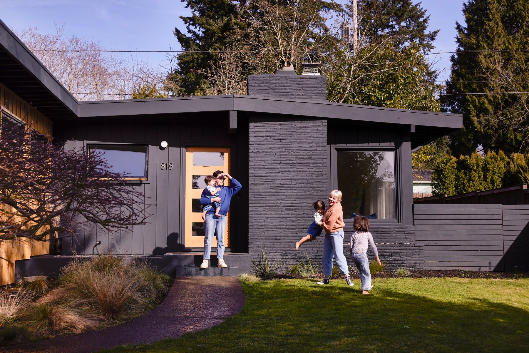 George Barberis Photograph of a family playing outside of their black mid century modern house family playing outside of midcentury house photo by photographer george barberis
