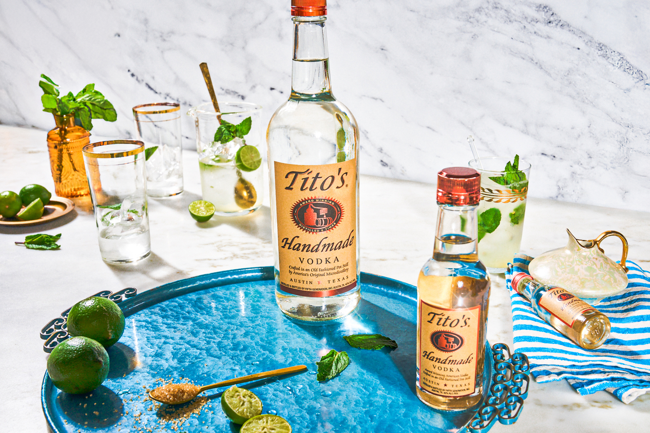 titos handmade vodka on metalic blue tray with mint leaves and limes on white marble photographed by knoxy knox