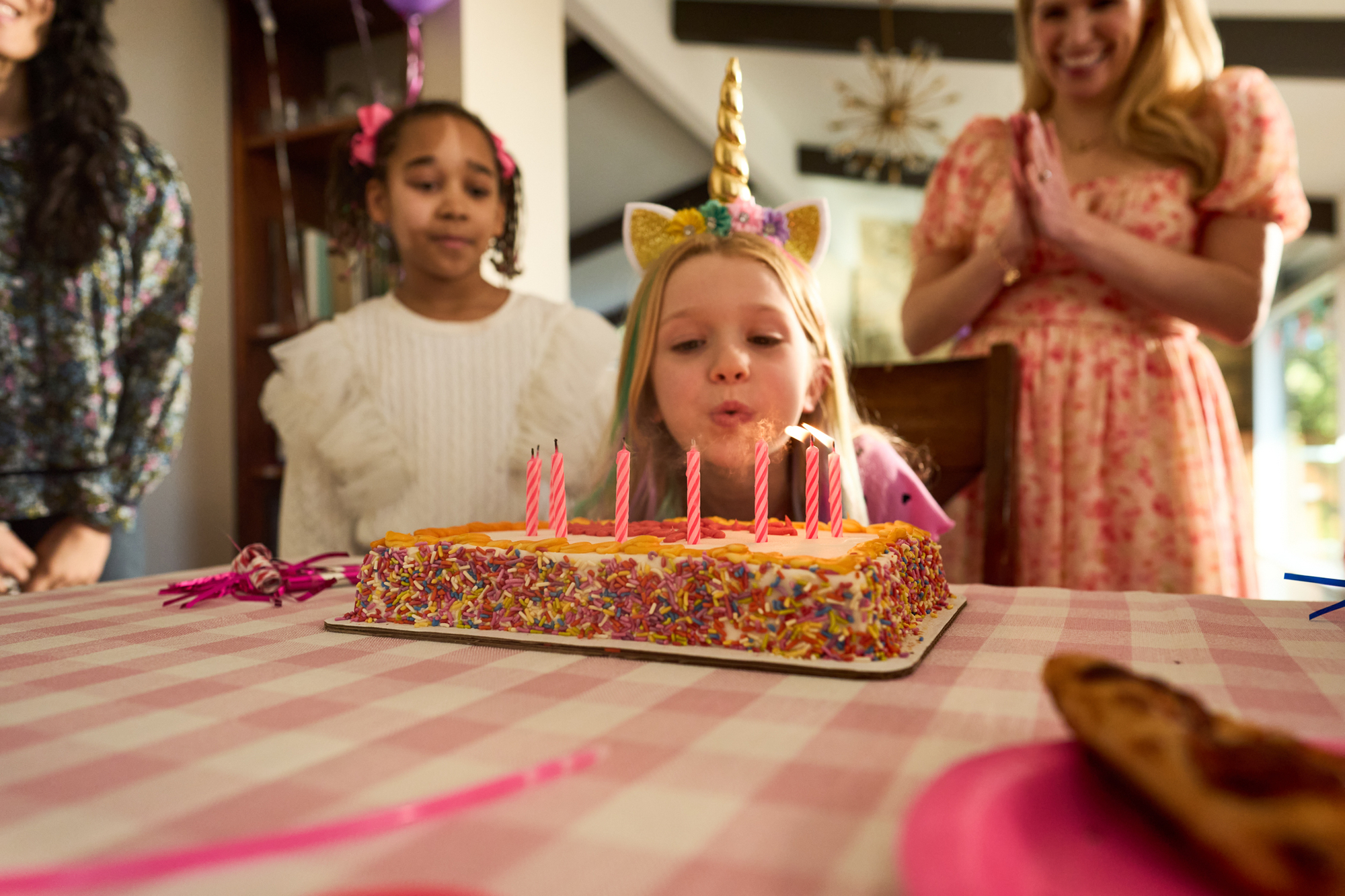 a little girl blows out the pink candles on her birthday cake Birthdays with ICCU