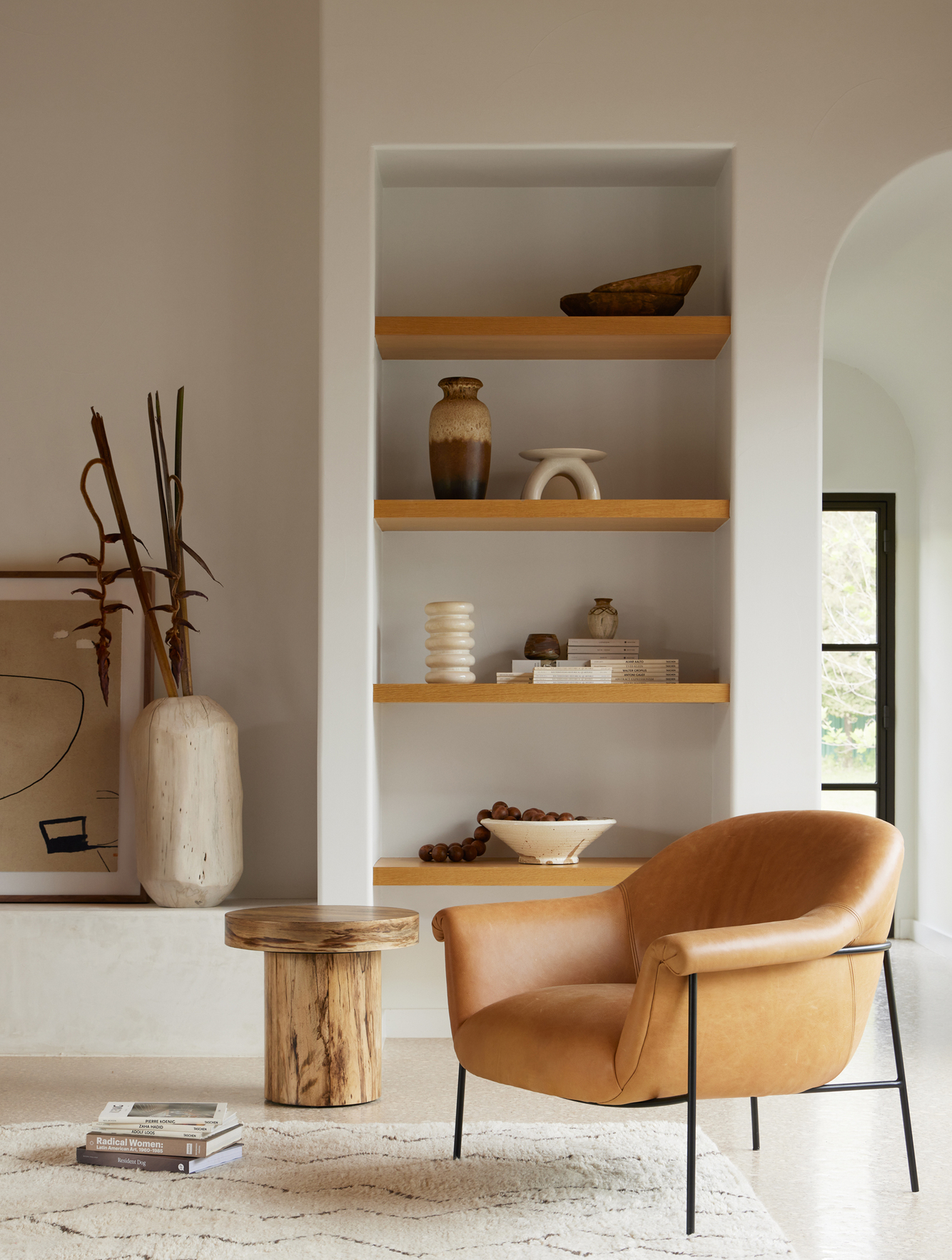 Brown leather chair in front of built in bookshelf with solid wood shelves on a cream wall