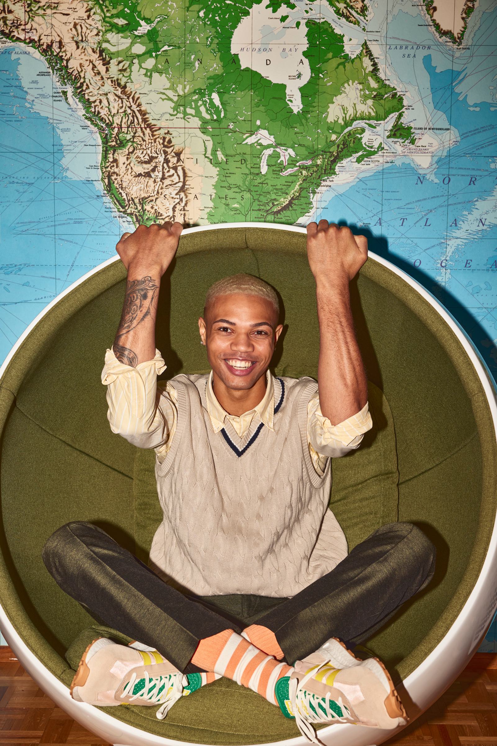man lounges in round green egg chair 