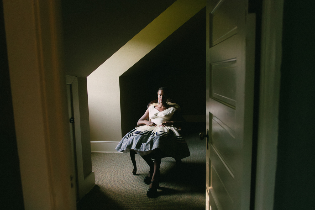 young black model in buzz cut sits in an attic chair 