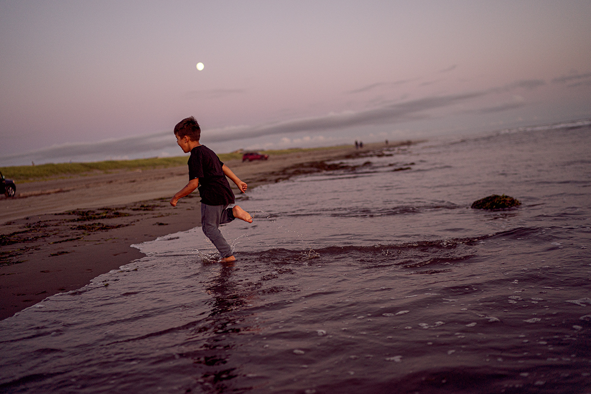 young boy running on the beach at dusk 