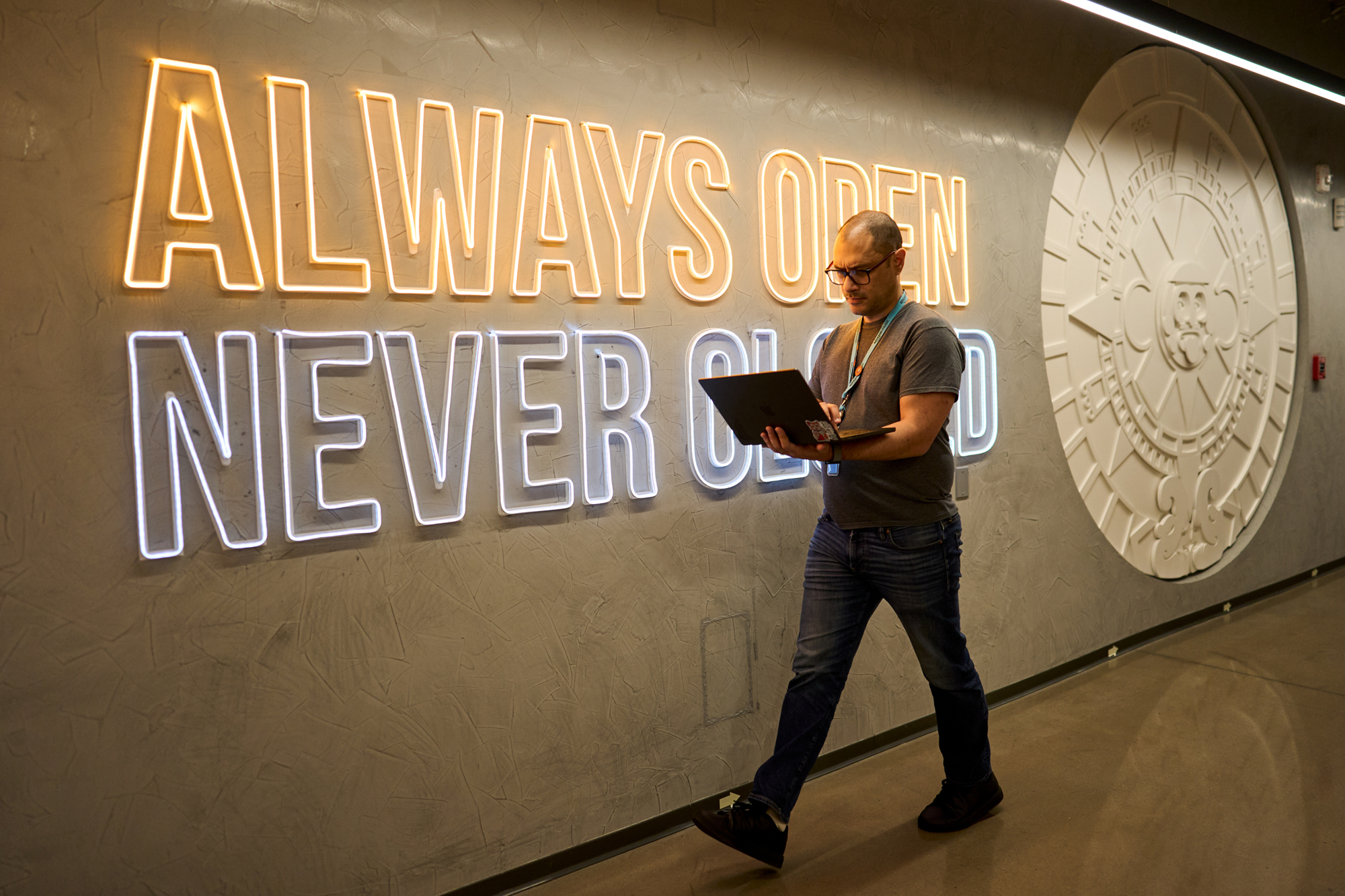 man walks by a sign as he works on his laptop at amazon 