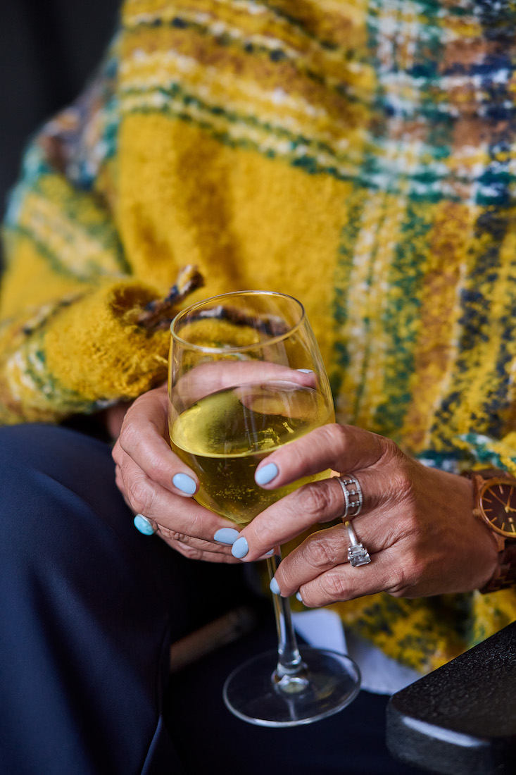 woman in yellow plaid poncho sips wine 
