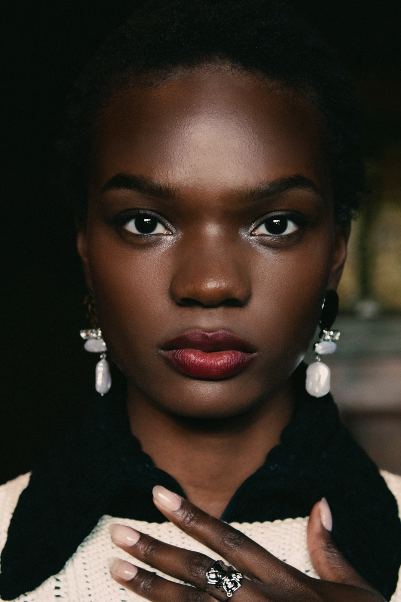 close up portrait of a young black model with a buzz cut and large pearl earrings 