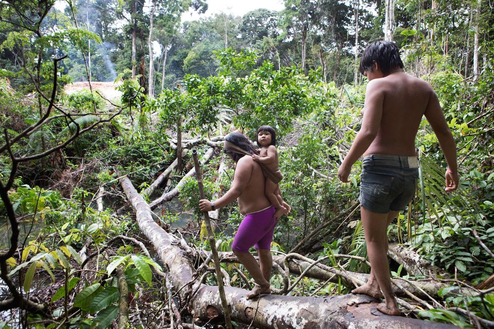 A young Korubo women Wio carries her child child Manisvo towards her Moloca. Amazon
