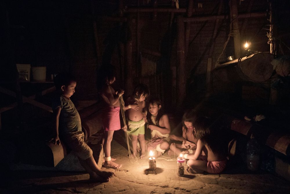Young Marubo children play and make waist and wrist bands inside the Maloca in the Village of Rio Novo. Amazon