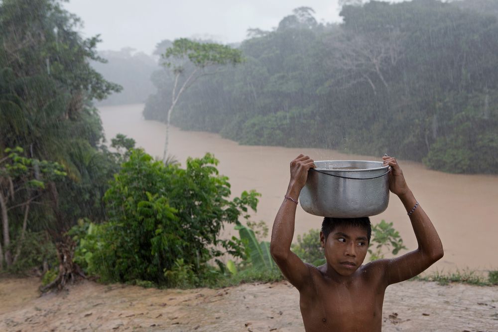 Young Marubo boy Metsisi Marubo carrying water from the Rio Itui toward the village of Rio Novo. Amazon