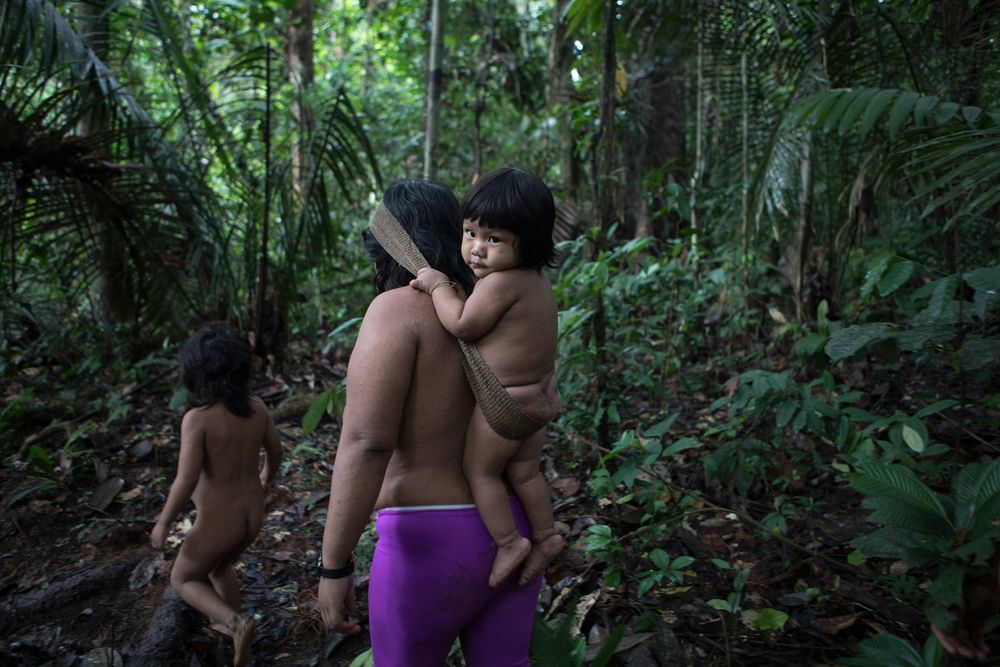 A young Korubo women Wio carries her child Manisvo through to their village towards her Moloca. Amazon