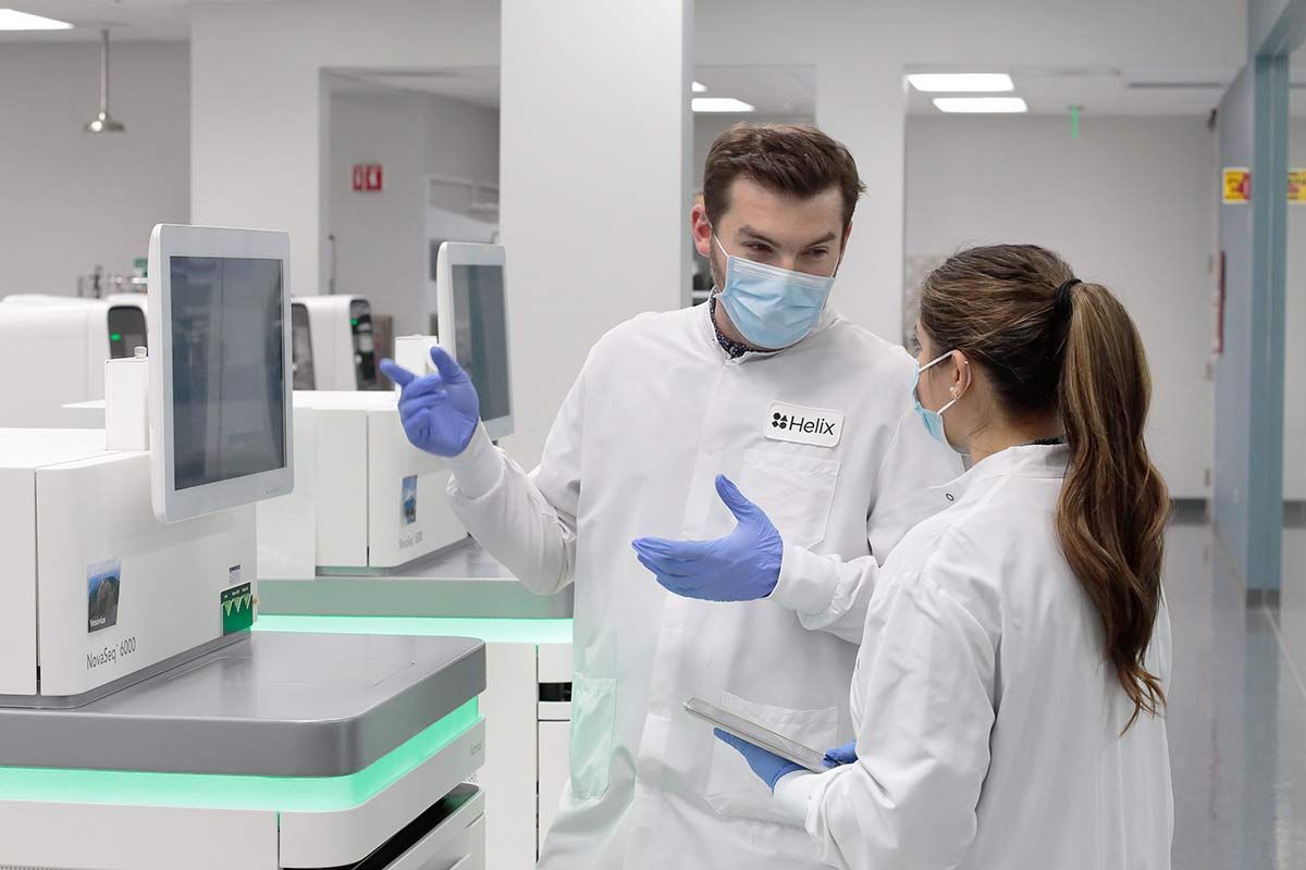 Biotech laboratory personnel discussing data next to sequencer