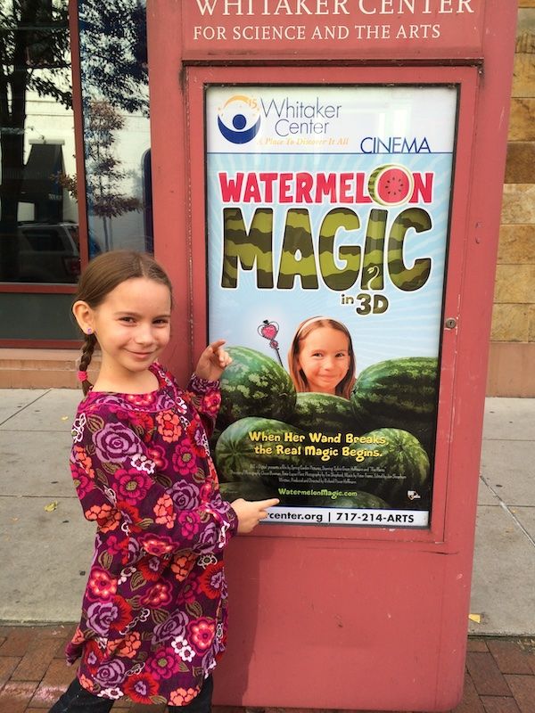 Sylvie poses beside a poster advertising screenings of Watermelon Magic in Harrisburg
