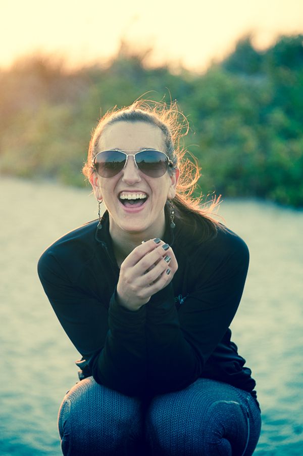 Gym trainer on location shoot at Hammonasset Beach with setting sun highlighting her hair. Krista Laughing on the Beach at Sunset