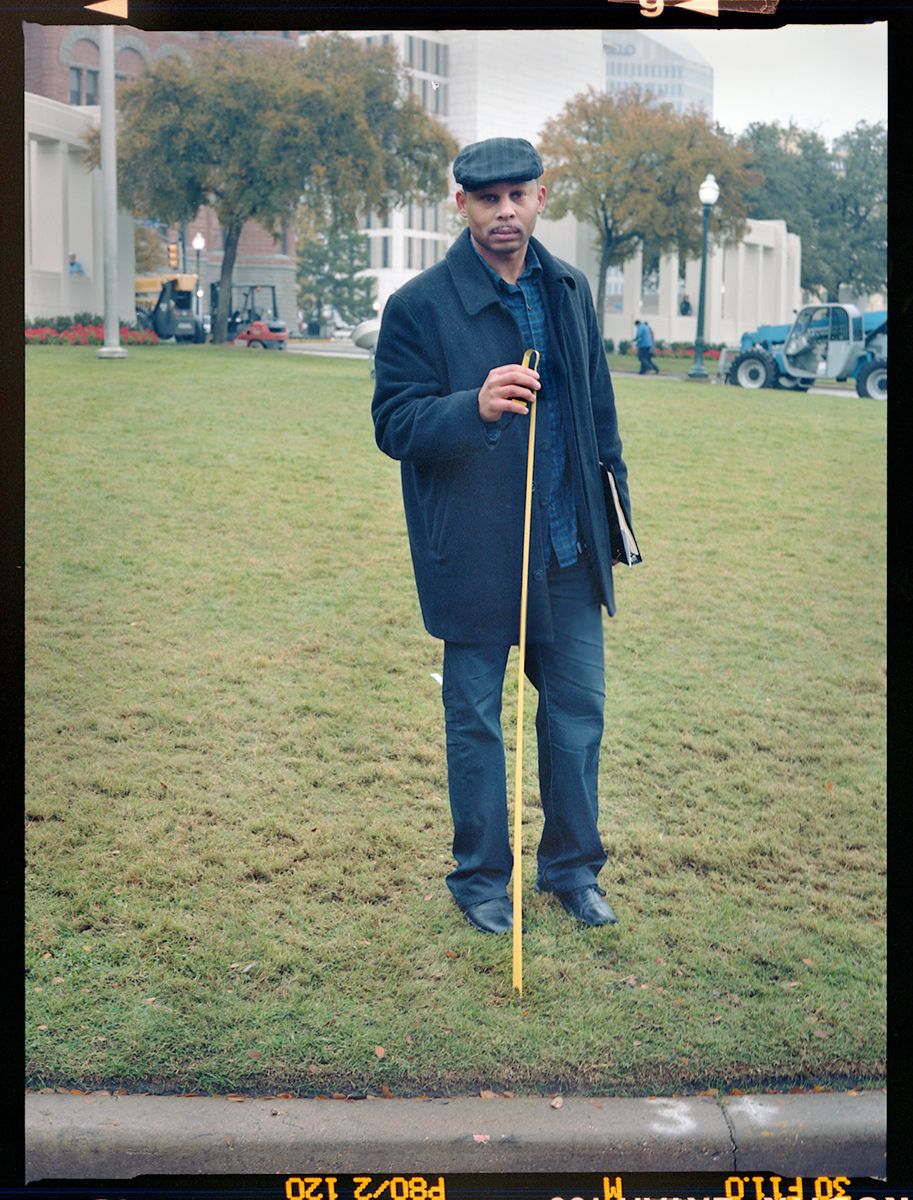 FRED JAMES, TAKING MEASUREMENTS BASED ON MARY MOORMAN'S VANTAGE POINT AT THE TIME SHE TOOK A POLAROID PHOTO OF THE MOTORCADE; HE IS TRYING TO PROVE A THEORY THAT THE ZAPRUDER FILM IS FAKED
