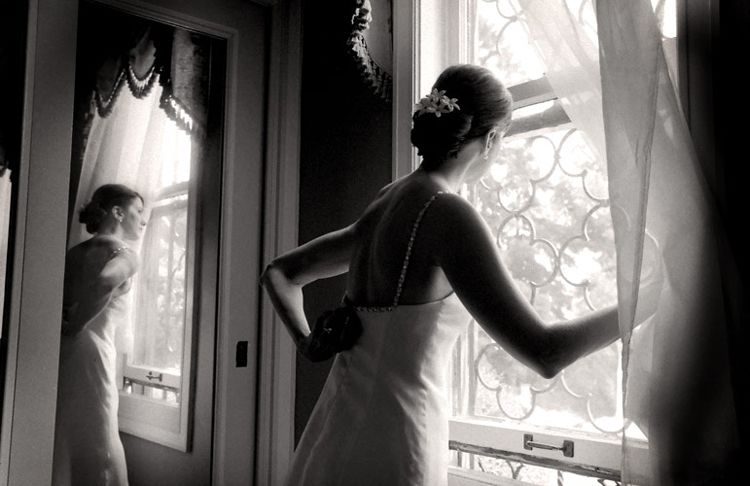 a bride loks out the window as she poses for getting ready wedding photos