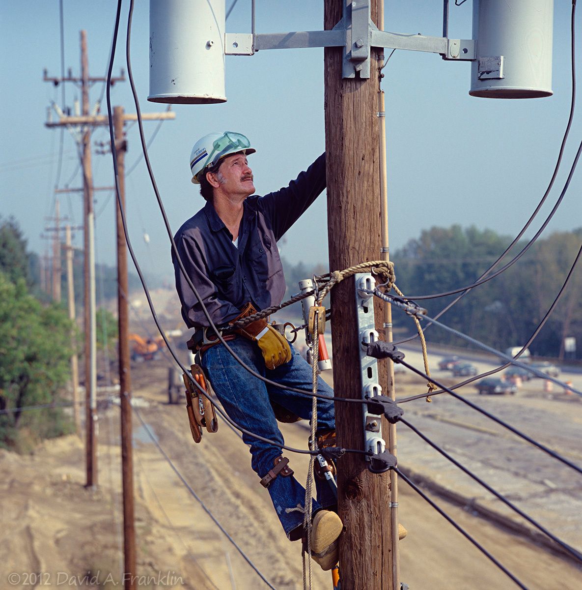 ElectricLineman_HerbTewilliager_WayUpOnPole_DoingRepairs_Michigan_Editorial