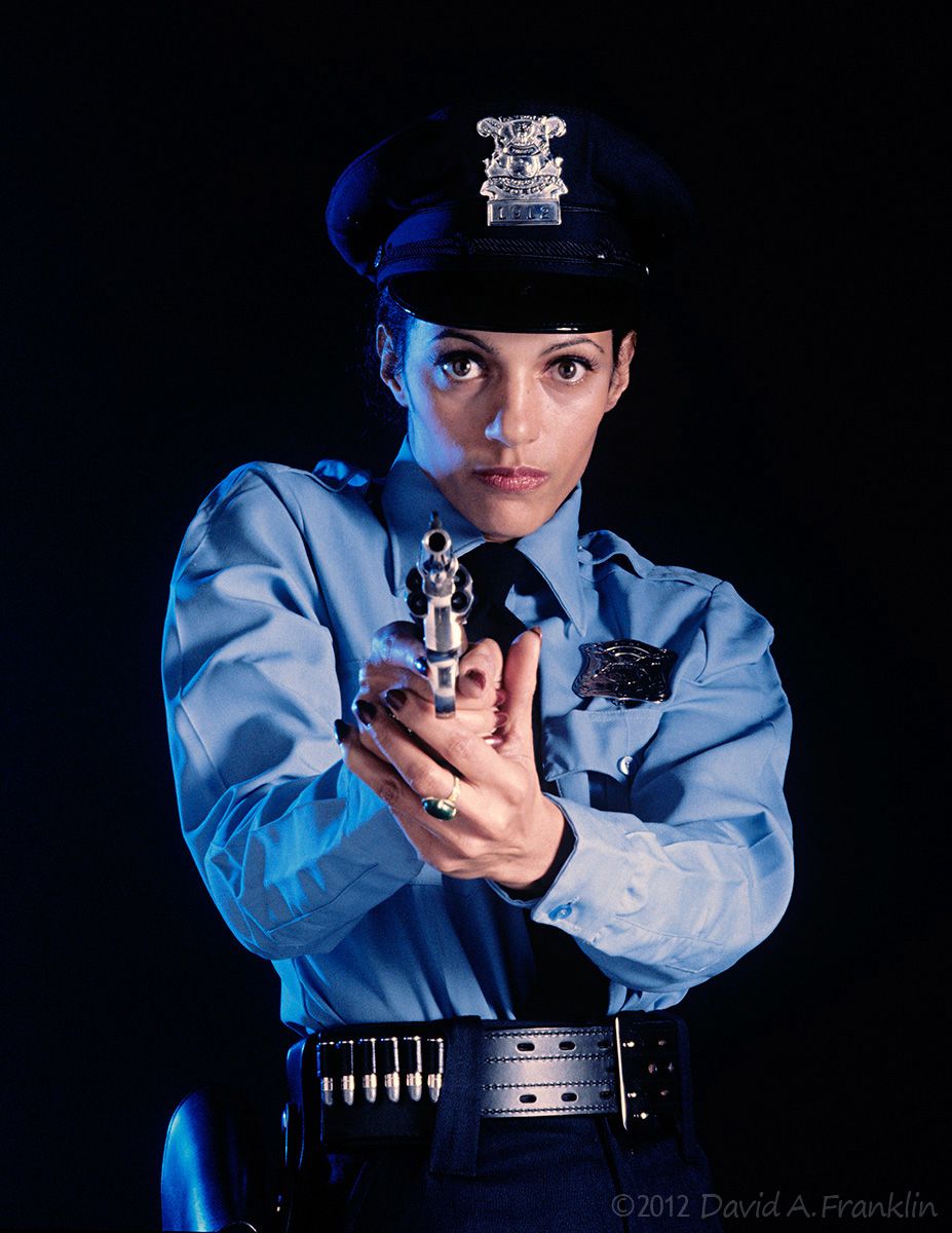 ModelAsFemalePoliceOfficer_GunPointedAtViewer_MagazineCover