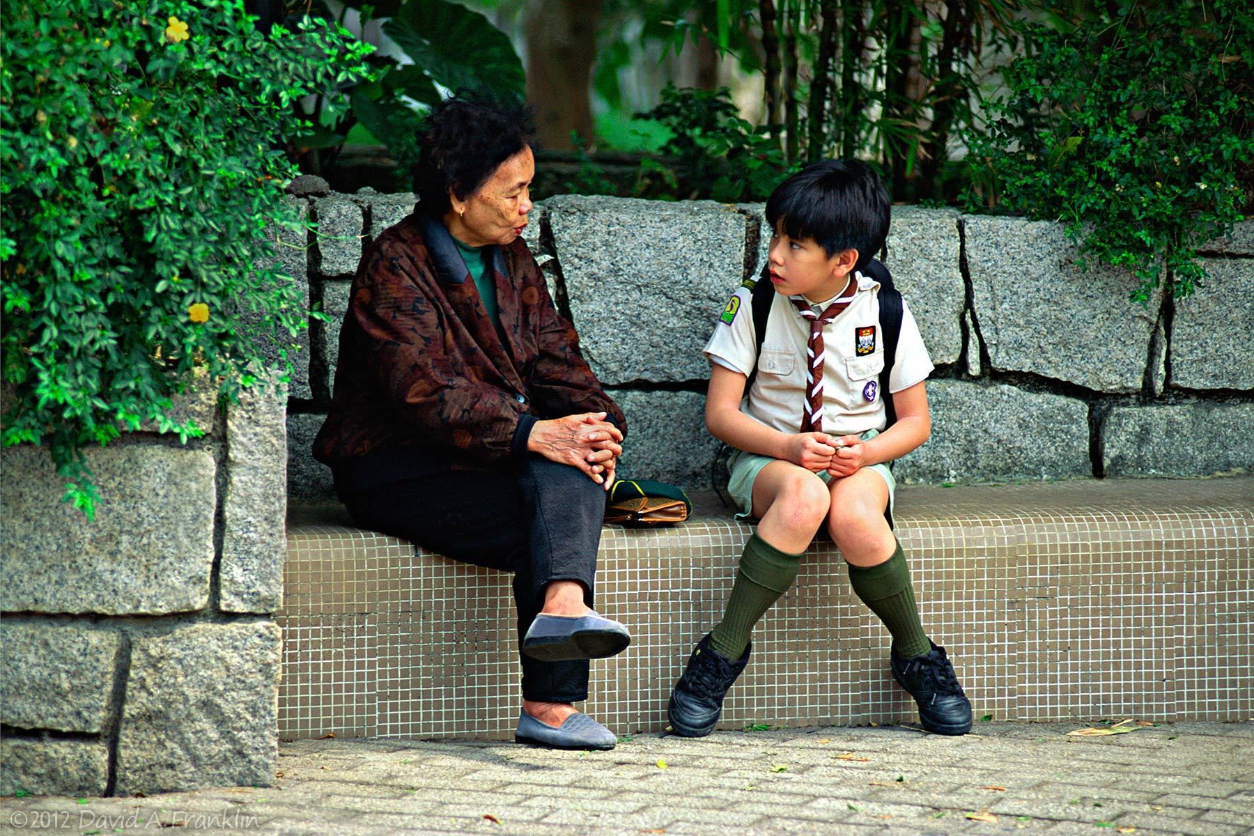 OlderLadyTalks_YoungBoyInScoutUniformListens_HongKong_Editorial