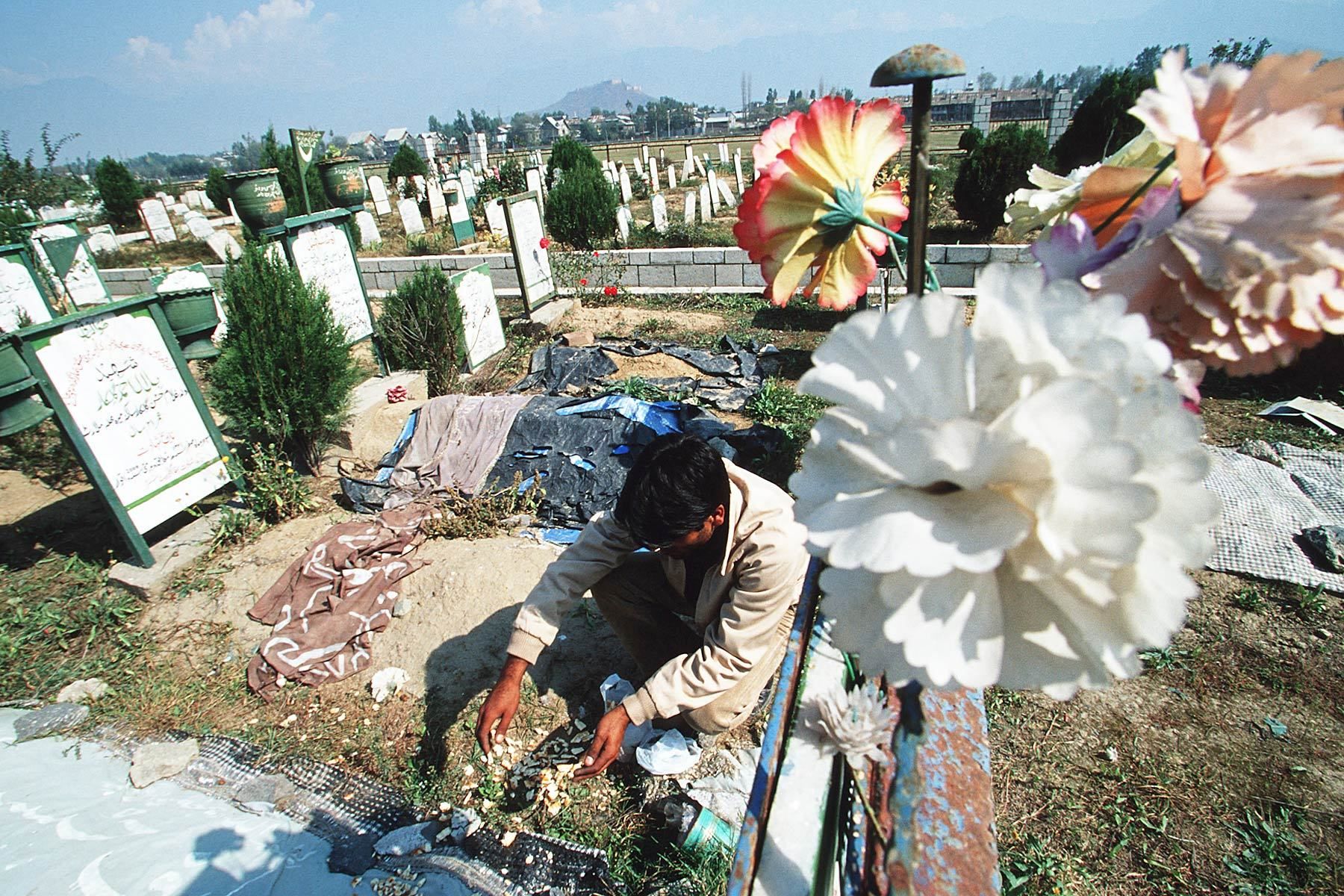 A man prays for his brother at war victim cemetary