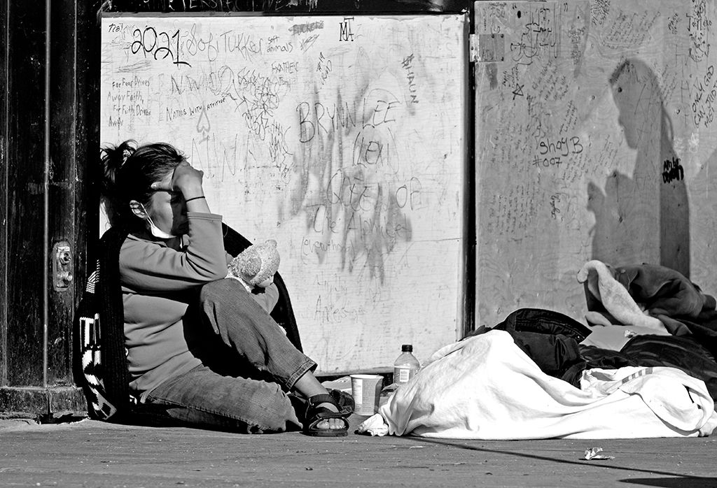 A woman sits outside the temporary homeless shelter at the Edmonton Convention Centre on April 30, 2021, when the  shelter was closed down. Hundreds of homeless people who had been living there over the winter months were forced to vacate the property.
