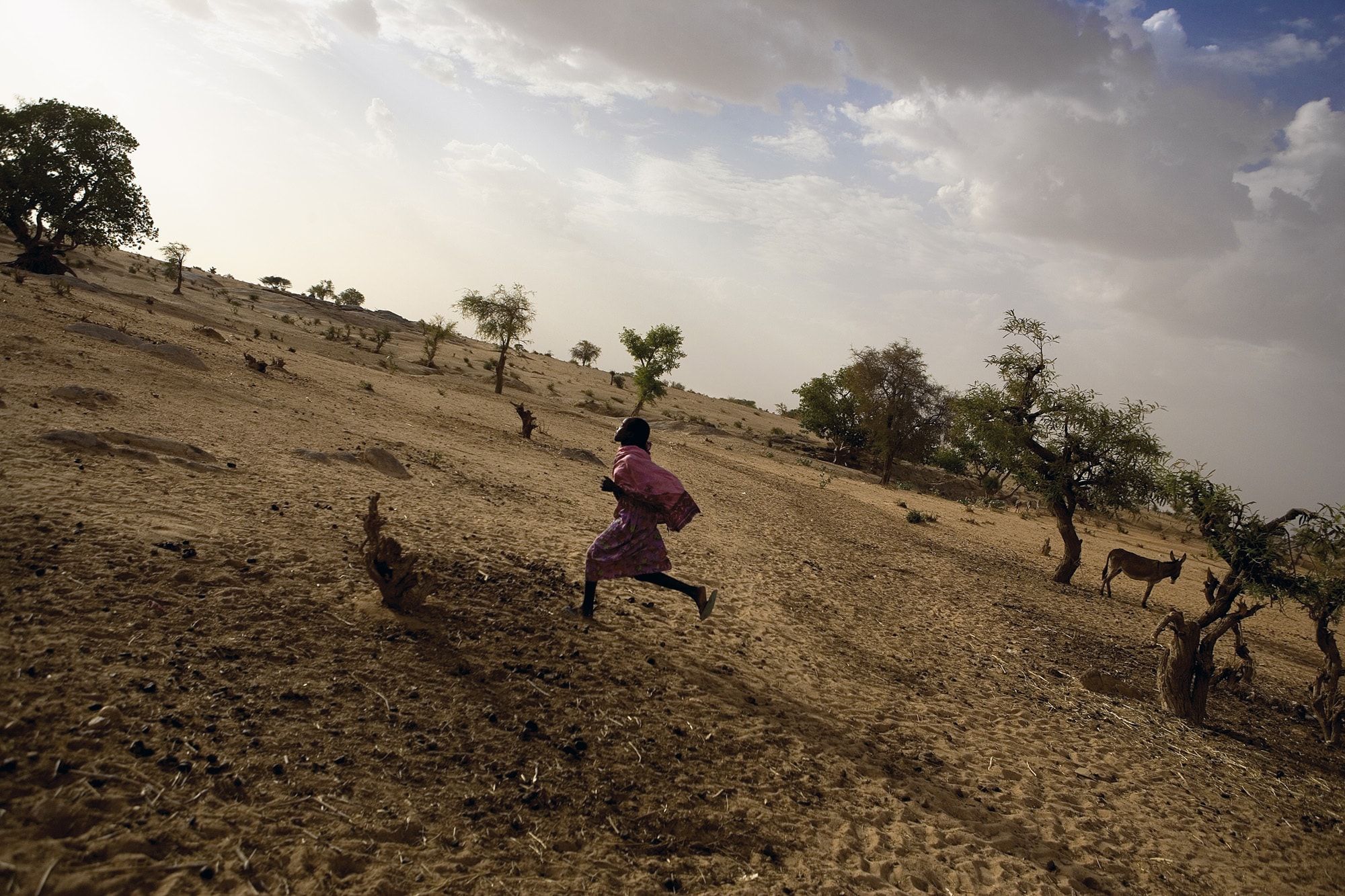 A Darfuri girl runs in a displacement camp.