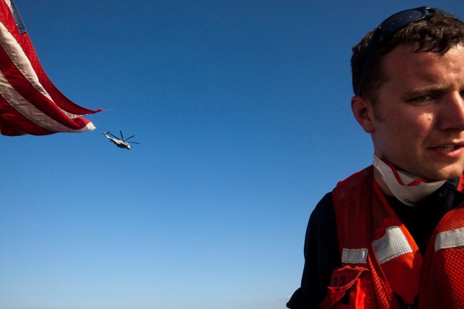 US Coast Guard personnel evacuate Haitians by boat to a helicopter.