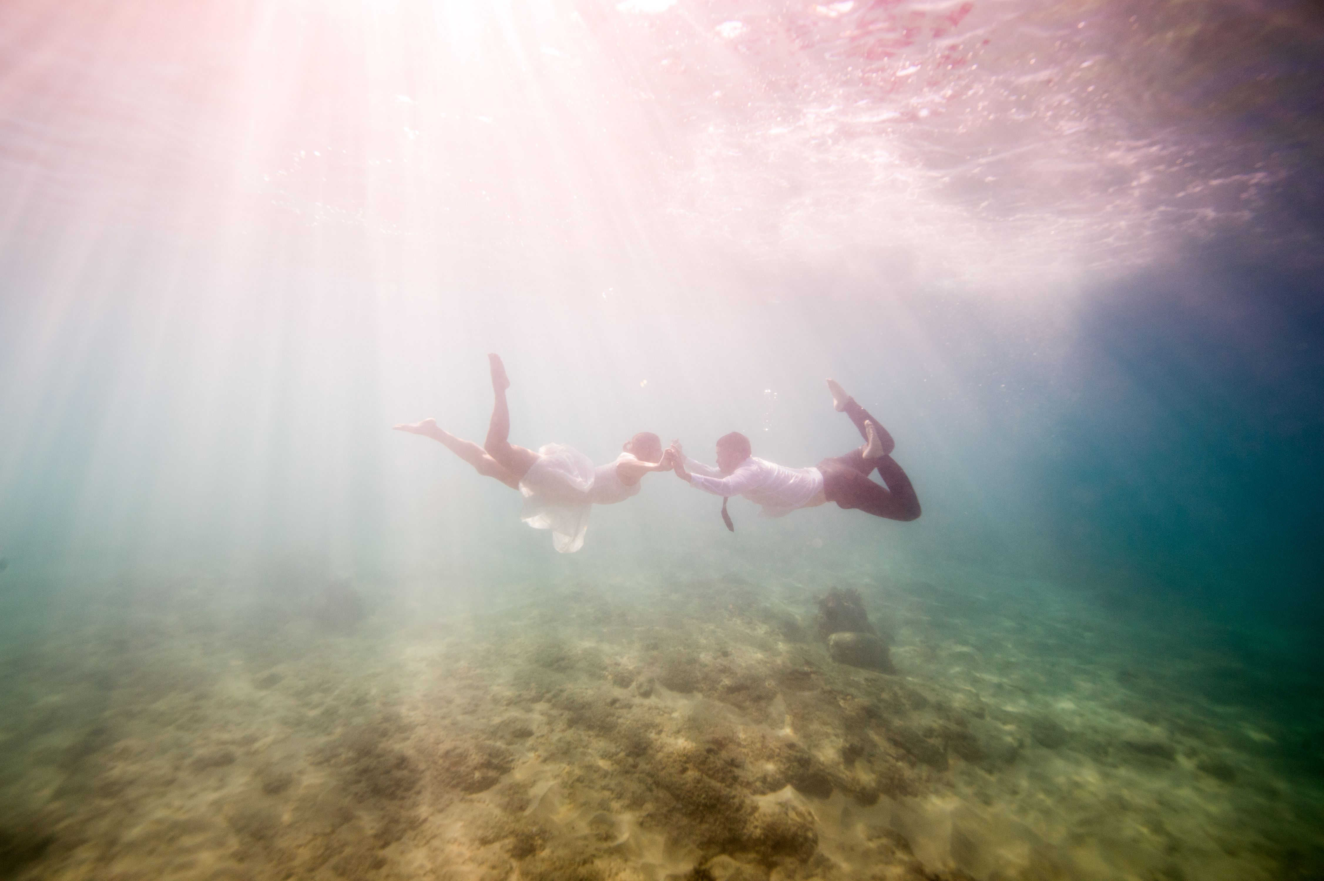 Underwater wedding photo with light beams from above