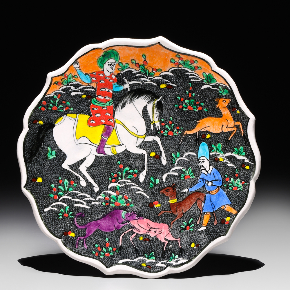 Auction photography of a hand-painted Turkish Kütahya ceramic plate with Ottoman-inspired hunting scene depicting mounted horseman, falconer, and hounds on black ground with polychrome floral border. Photographed for I.M. Chait Gallery and Auctioneers and featured on LiveAuctioneers by Los Angeles commercial photographer Victor Koroma. Turkish Kütahya Ottoman Ceramic Plate Hunting Scene — I.M. Chait LiveAuctioneers Victor Koroma