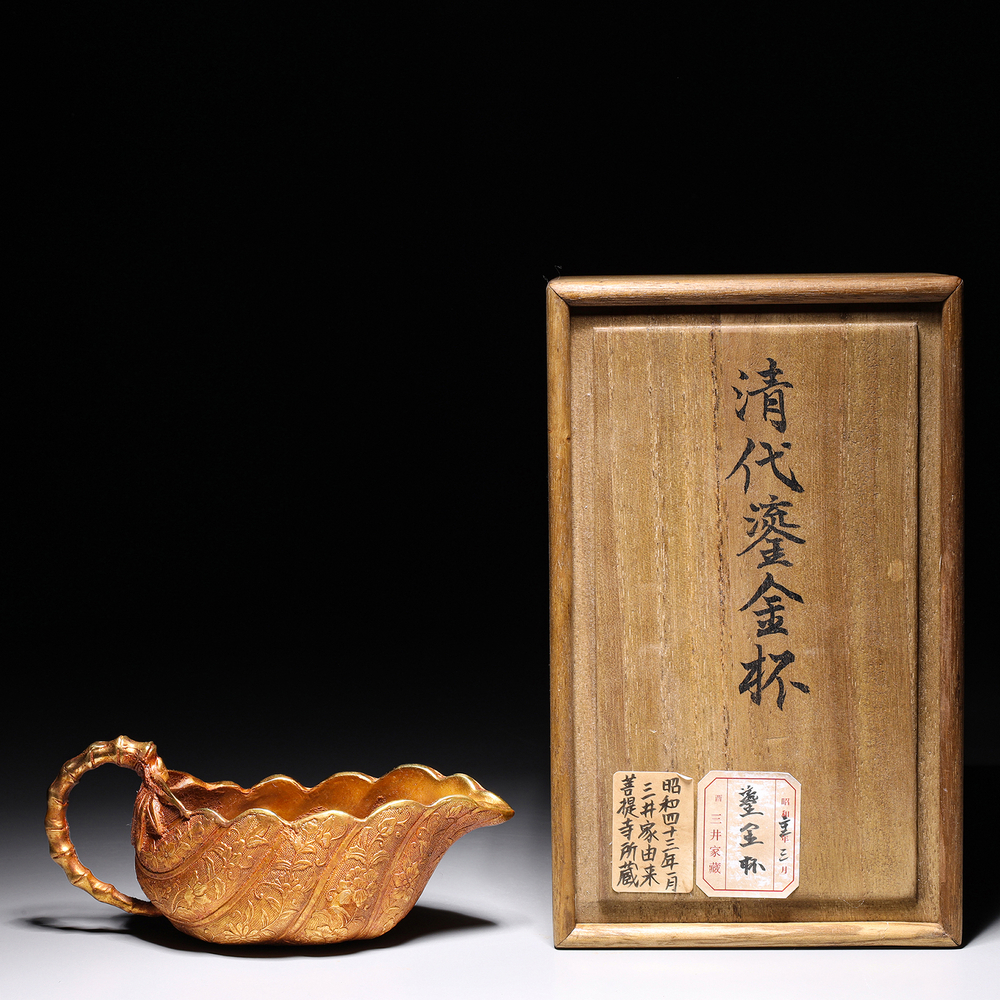 Auction photography of a Qing Dynasty gilded bronze cup with repoussé floral decoration and bamboo handle, with original Japanese provenance inscribed wooden storage box. Photographed for I.M. Chait Gallery and Auctioneers and featured on LiveAuctioneers by Los Angeles commercial photographer Victor Koroma. Qing Dynasty Gilded Cup with Wooden Box — I.M. Chait LiveAuctioneers Victor Koroma