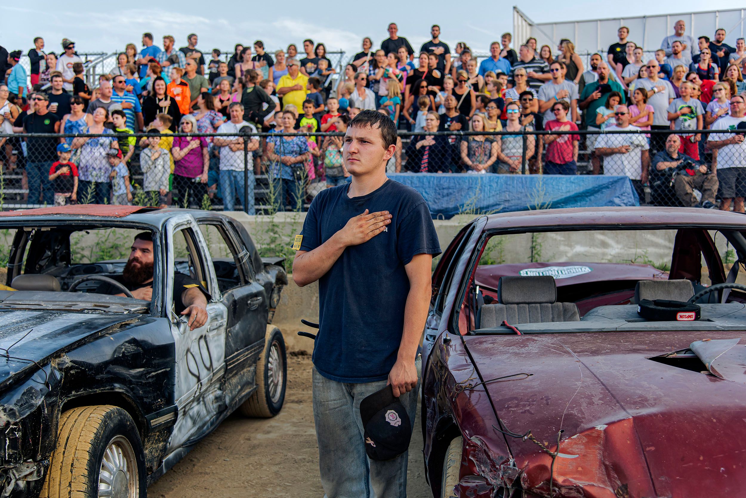Young man with his hand over his heart as they raise the flag and play America the Beautiful at the demo derby event. Marshfield County Fair, Marshfield, MA Marshfield County Fair