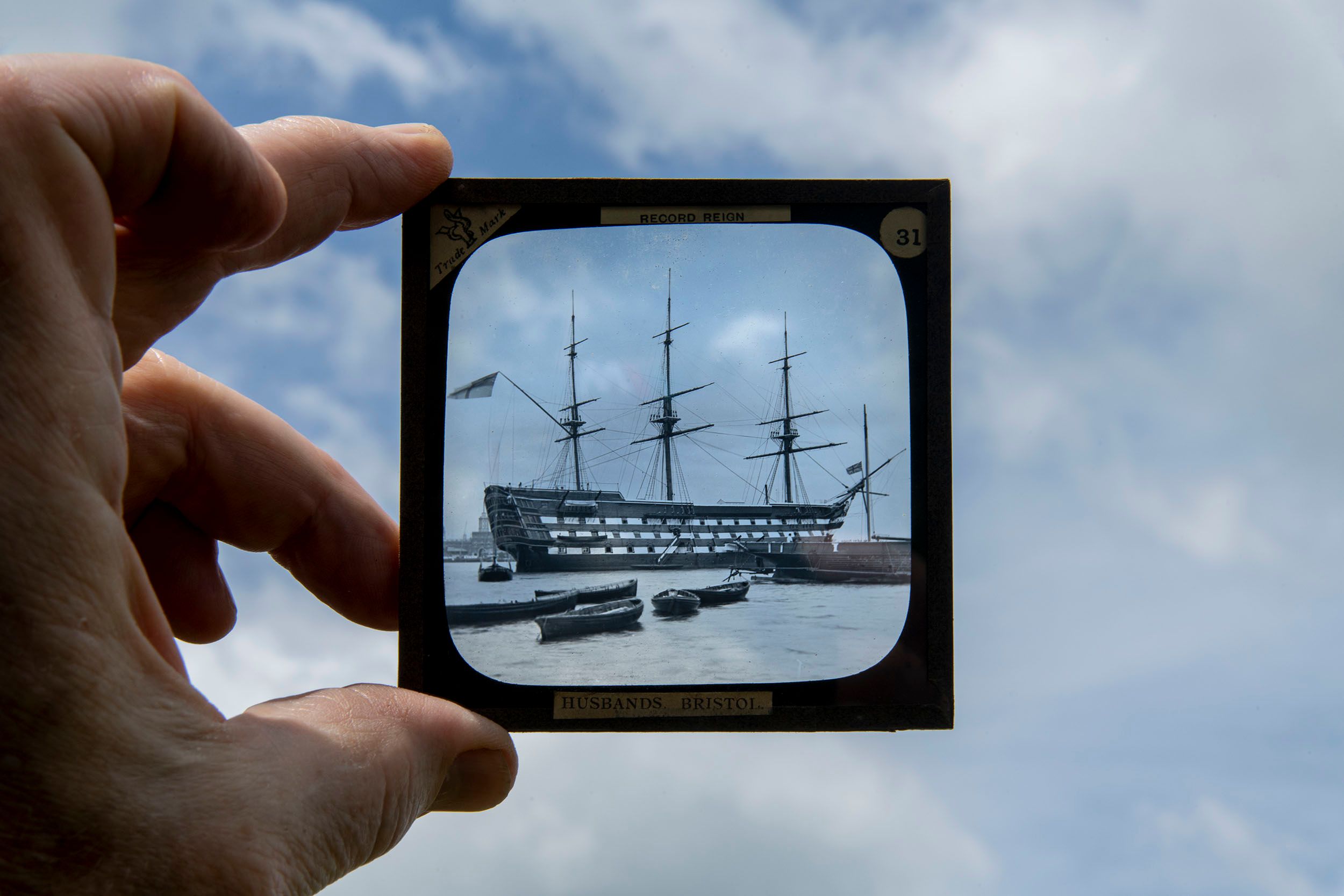 Photograph of a photograph held against the sky of an old sailing ship. Bizarroland