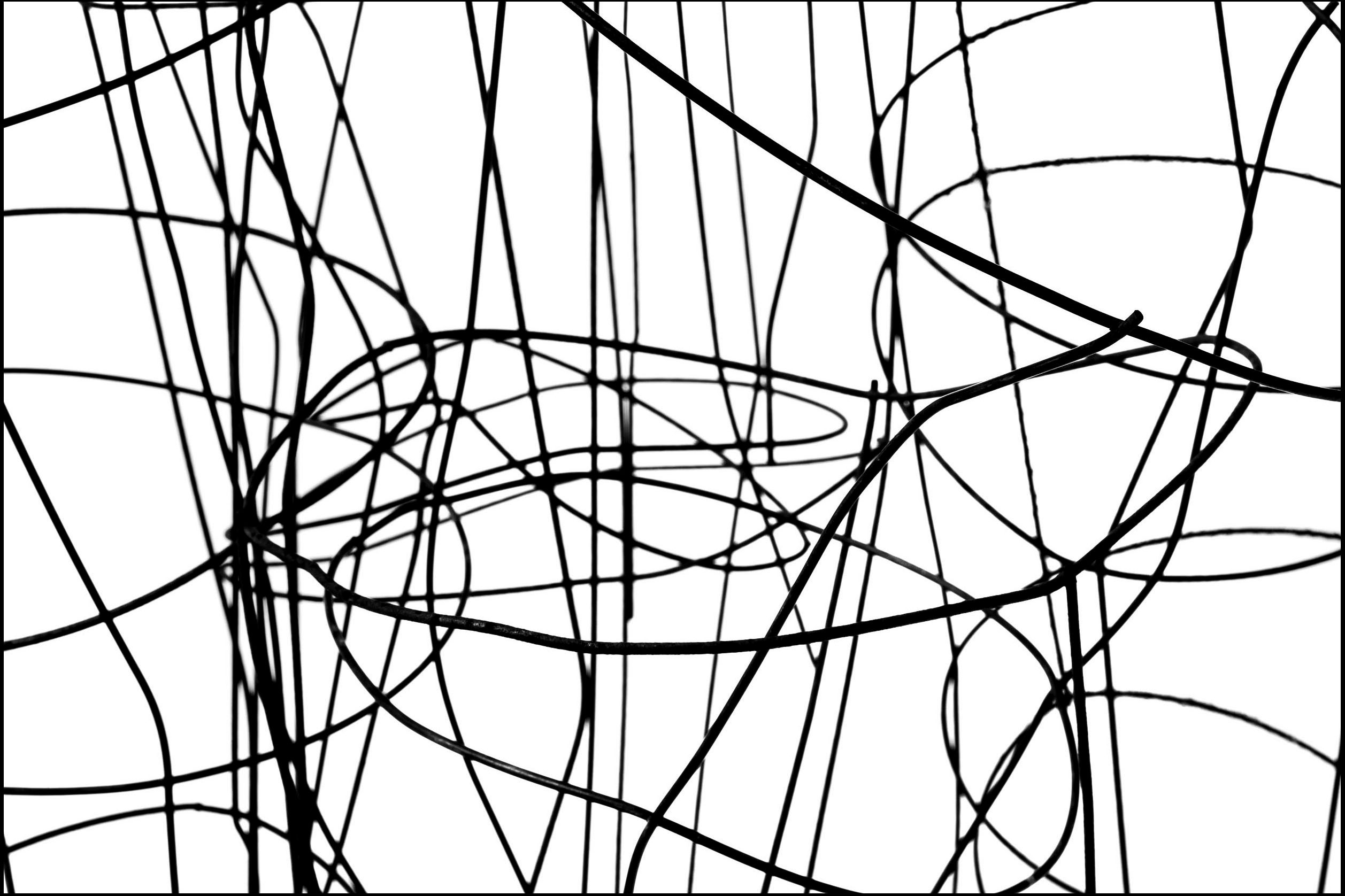 Black and white abstract photograph of twisted steel wire against white background. Twisted Wire