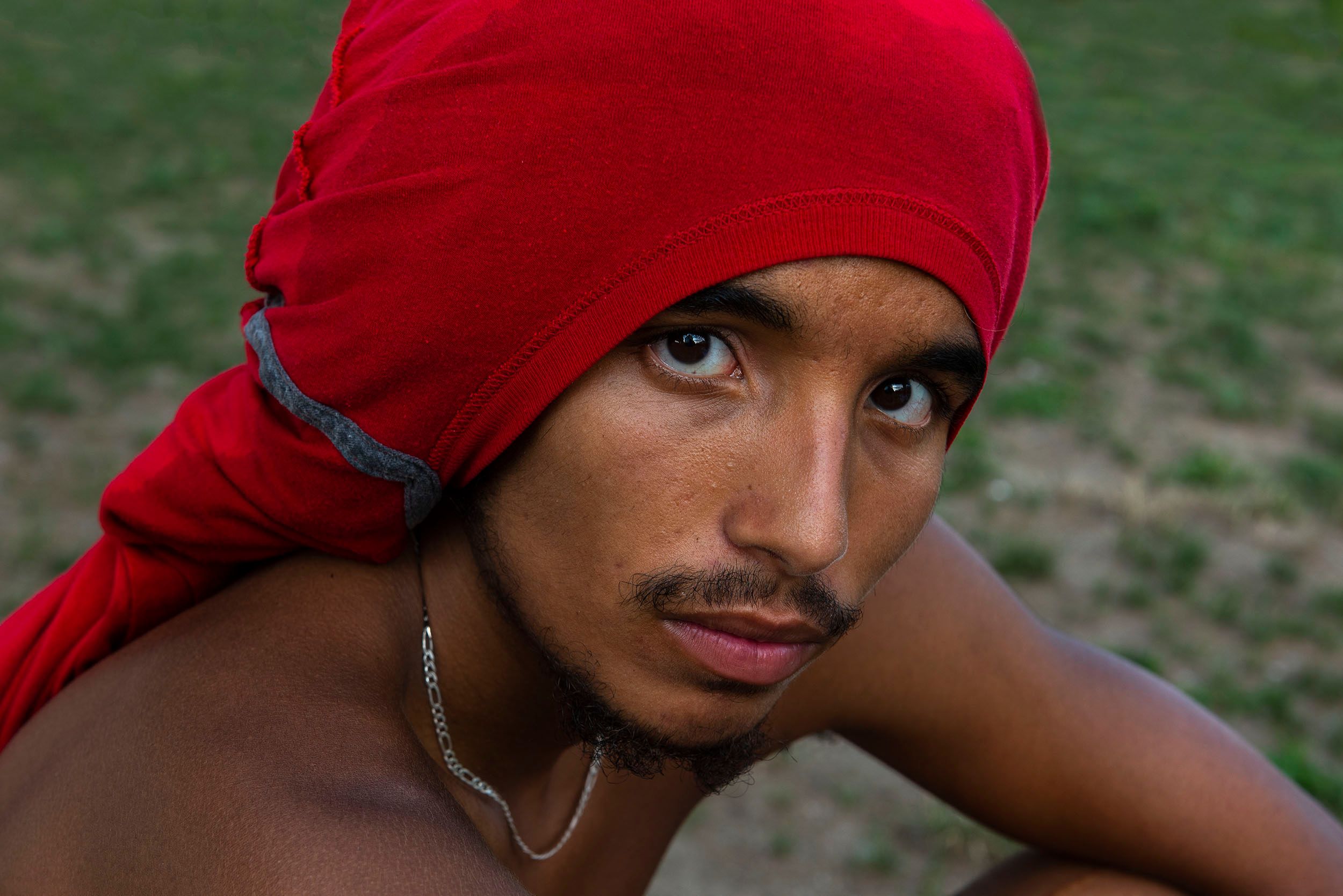 Color photograph of Carlos, a skateboarder with a red shirt on his head at the Lynch Family Skateboard Park, Cambridge, MA Portrait of Carlos