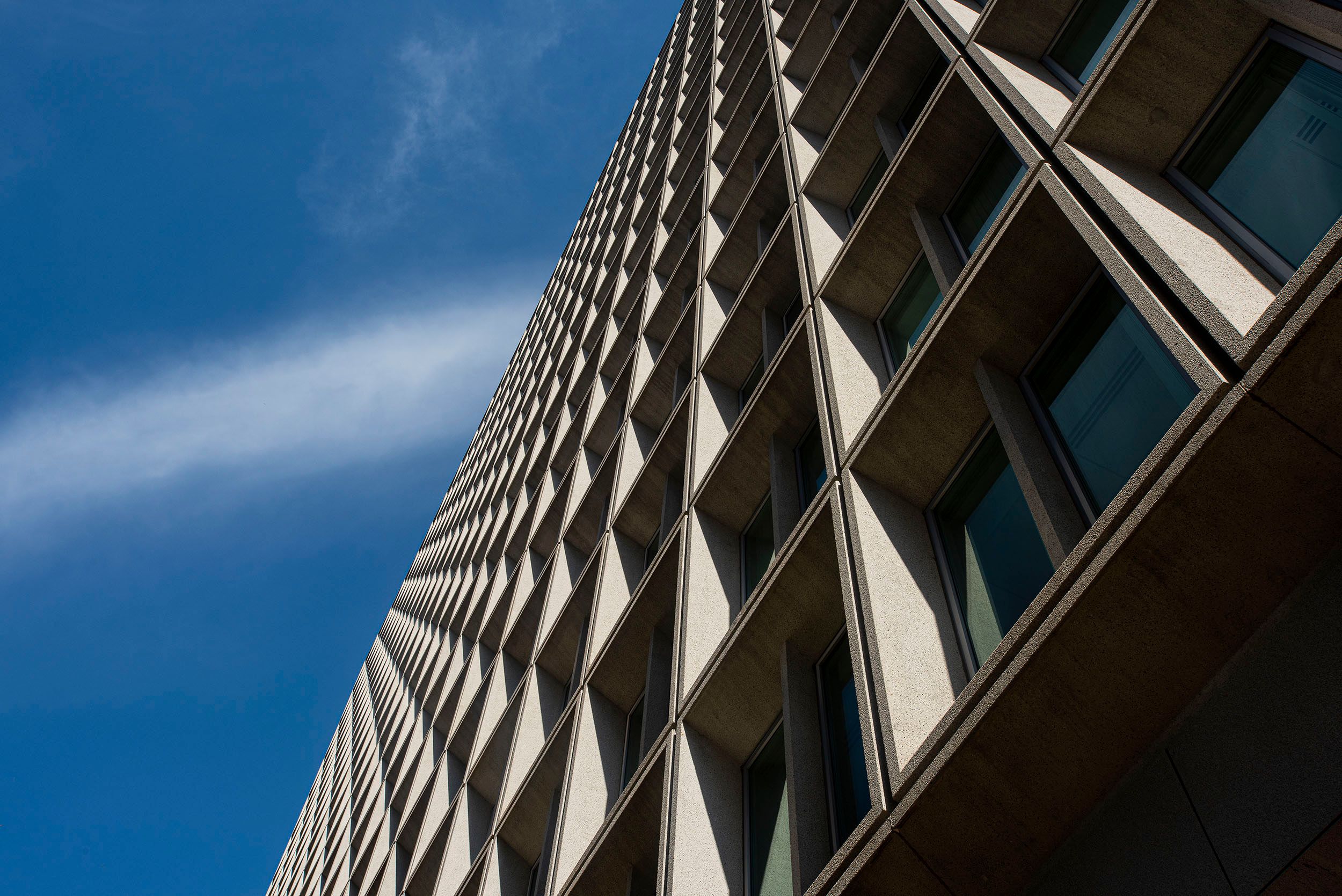 Photograph of the facade of a building with a white cloud streaking across the blue sky during the coronavirus pandemic. Boston, MA Coronavirus in the sky