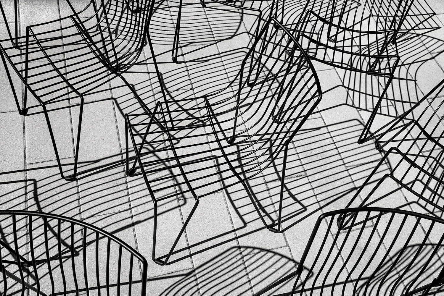 Black and white photograph of metal wire chairs and their shadows creating abstract lines and shapes. Cambridge, MA Abstract Chairs and Shadows