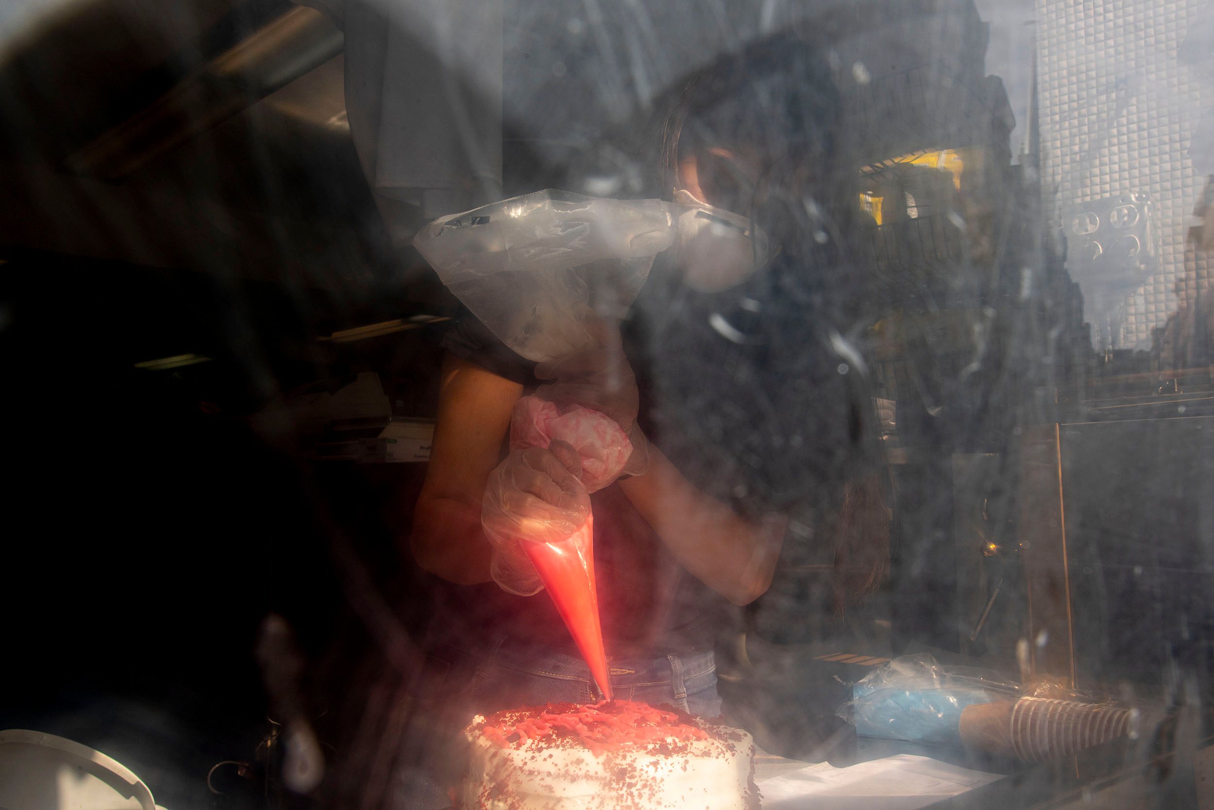Photograph of a pastry chef in a window putting the final touches of frosting on a cake in a bakery in the North End. Boston, MA Frosting on the cake