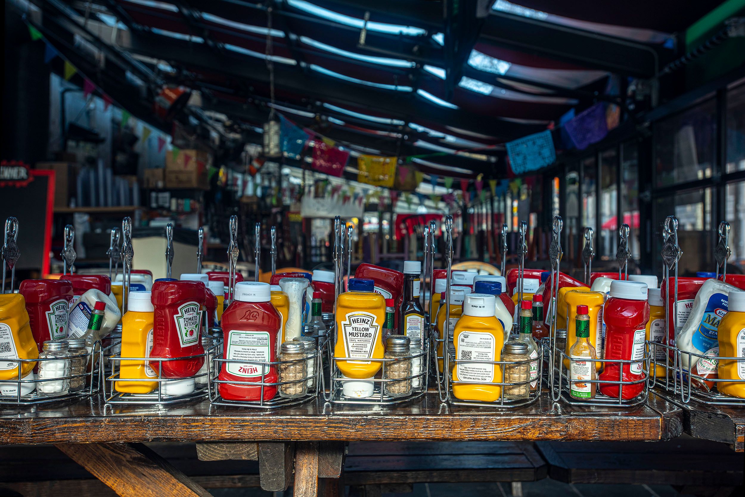 Photograph of a table filled with mustard and ketchup containers, salt and pepper waiting for customers to fill the tables again. Boston, MA Waiting for customers
